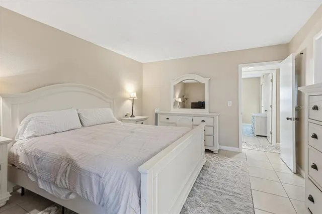 a spacious bedroom with a bed a mirror and a dresser