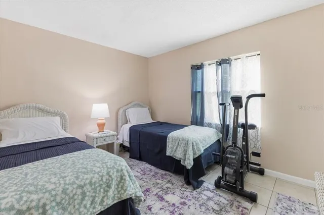 a bedroom with a bed table chair and a window