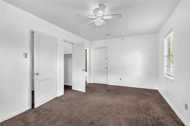 a view of empty room with window and ceiling fan