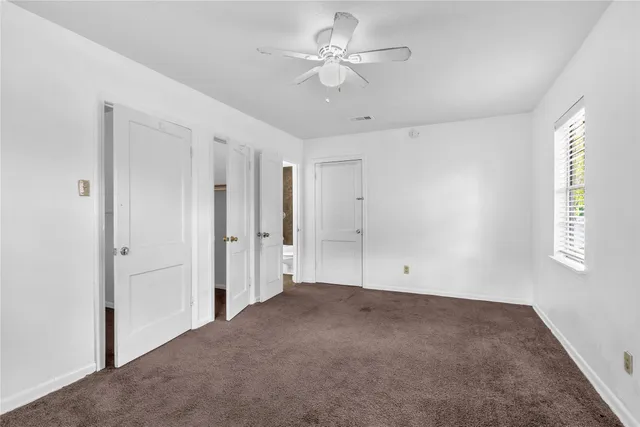 a view of empty room with window and ceiling fan