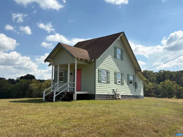 a front view of house with yard and trees in the background
