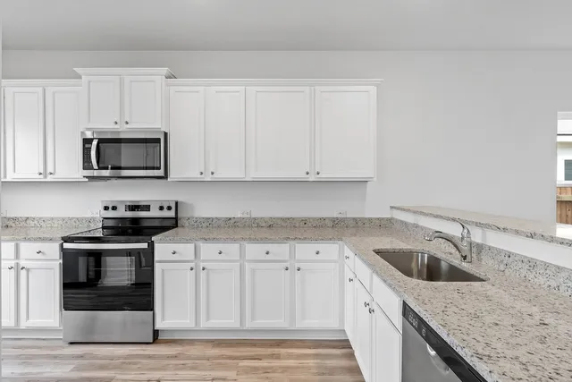 a kitchen with granite countertop white cabinets sink and stainless steel appliances