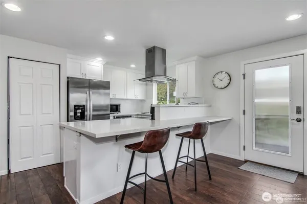 a kitchen with stainless steel appliances a dining table chairs refrigerator and cabinets