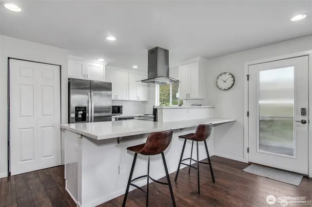 a kitchen with stainless steel appliances a dining table chairs refrigerator and cabinets