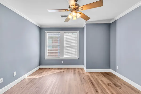 a view of an empty room with window and wooden floor
