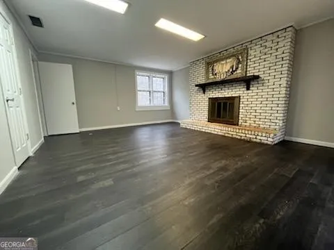 an empty room with wooden floor a fireplace and windows