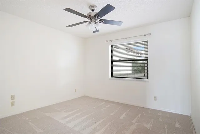 an empty room with a window and a ceiling fan
