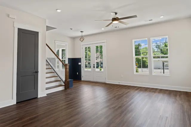 a view of a livingroom with wooden floor a ceiling fan and windows