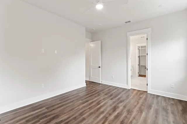 a view of an empty room with wooden floor and closet