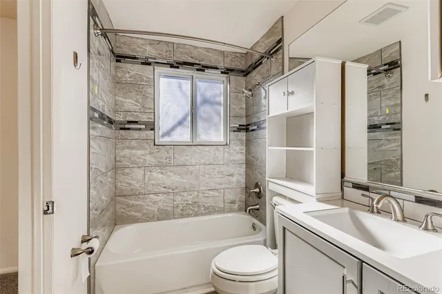 a bathroom with a granite countertop bathtub shower sink vanity and toilet