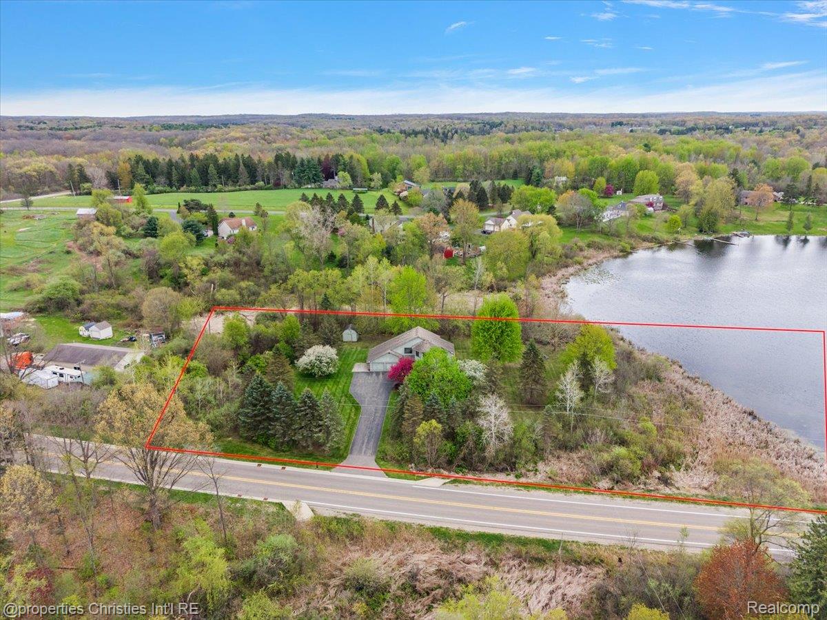 6175 Tripp Road Holly, MI 48442 - Photo 58 of 63 Aerial perspective showcasing a property with extensive lake frontage, mature trees, and a paved driveway