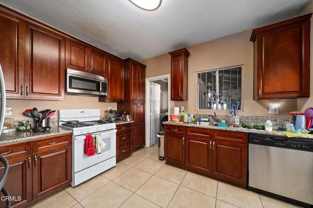 a kitchen with granite countertop stainless steel appliances a sink stove top oven and cabinets