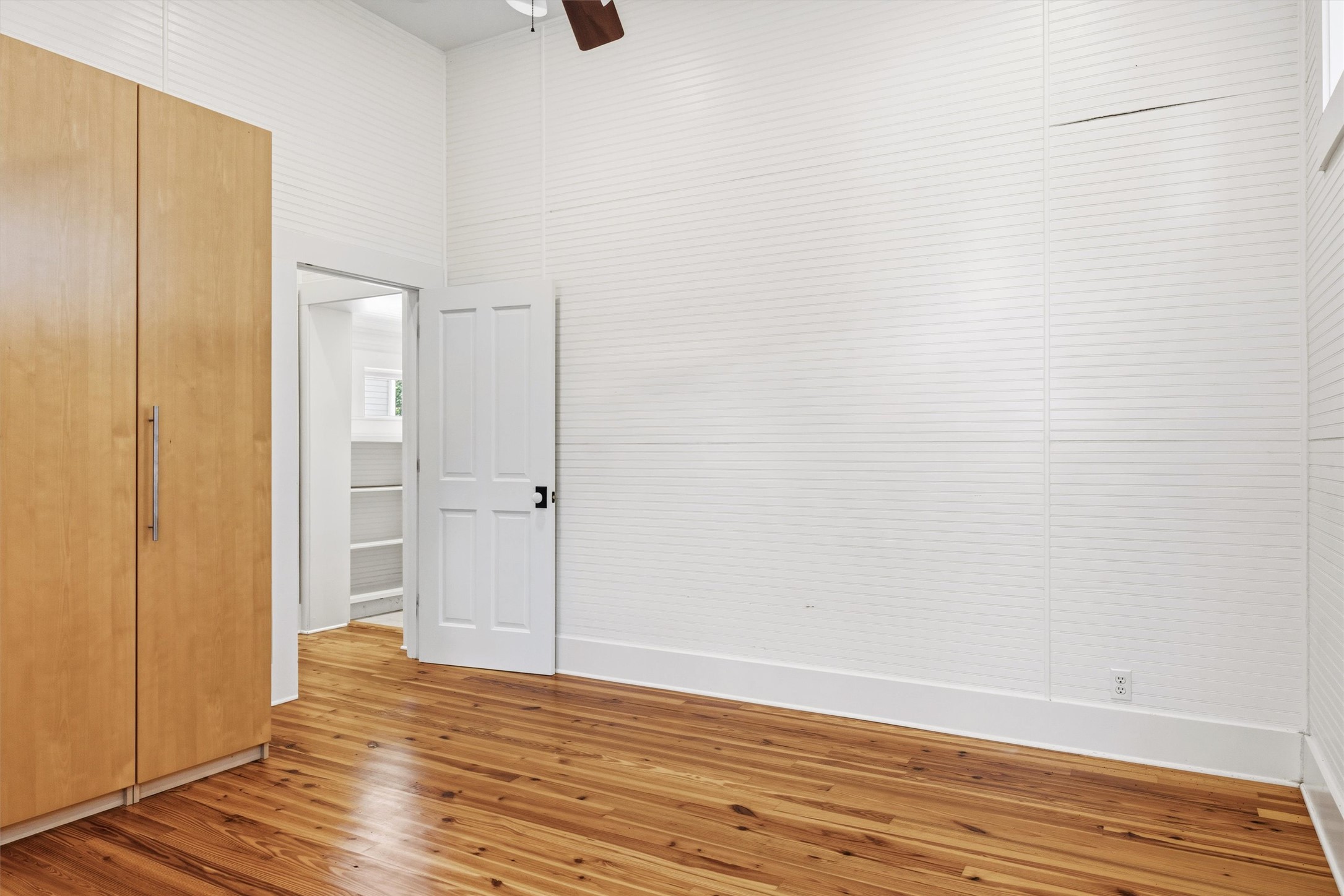 1613 Drake Avenue Austin, TX 78704 - Photo 19 of 27 Room featuring wood-finish flooring, white horizontal wall paneling, and a ceiling fan