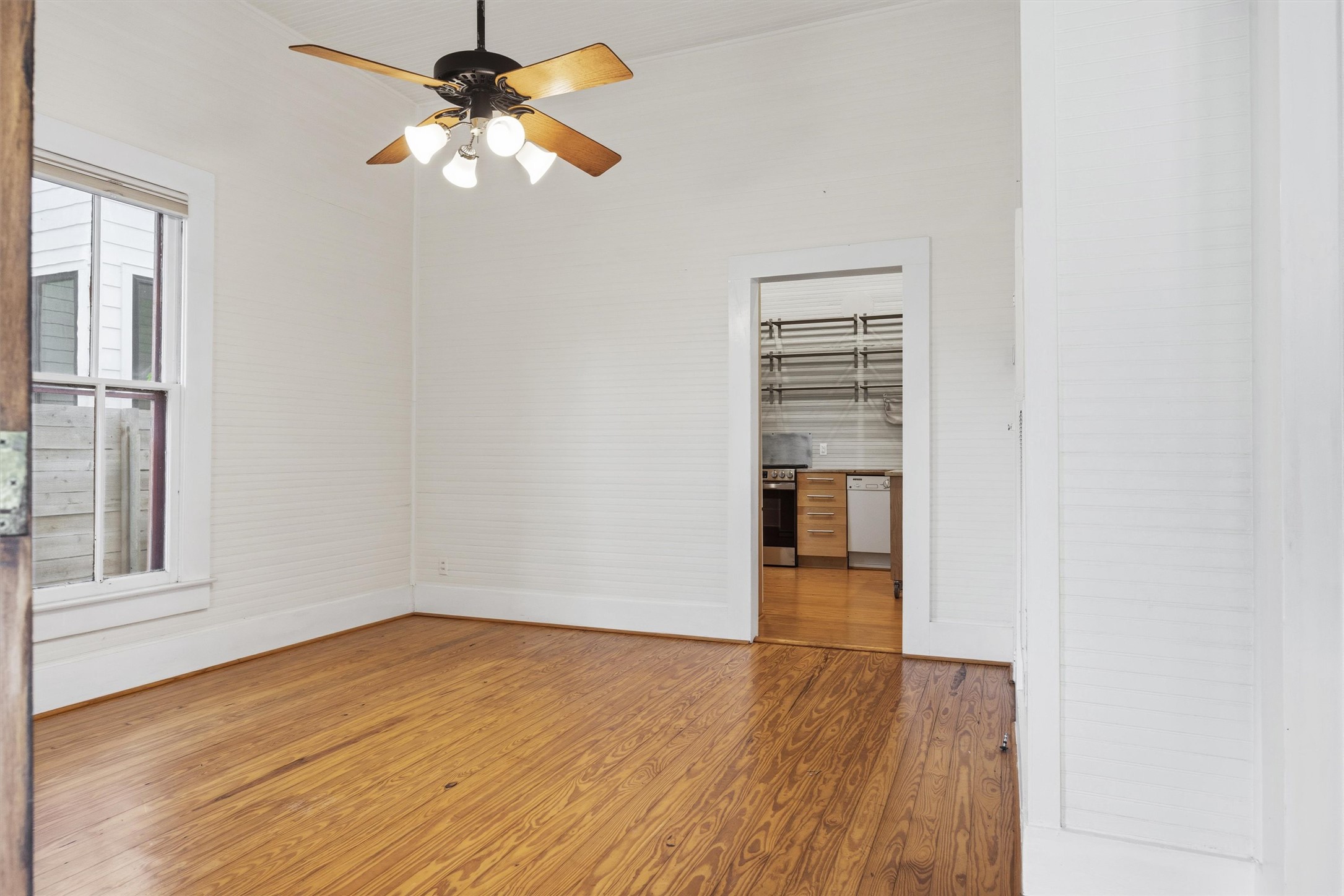 1613 Drake Avenue Austin, TX 78704 - Photo 6 of 27 Bright room featuring wood-finish flooring, white horizontal wall paneling, and a multi-light ceiling fan