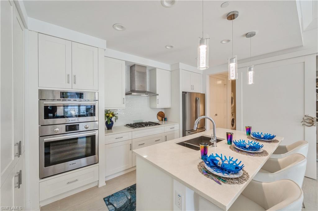 1135 3rd Avenue South, Unit 304 Naples, FL 34102 - Photo 10 of 35 Kitchen featuring white cabinetry, wall chimney exhaust hood, and stainless steel appliances