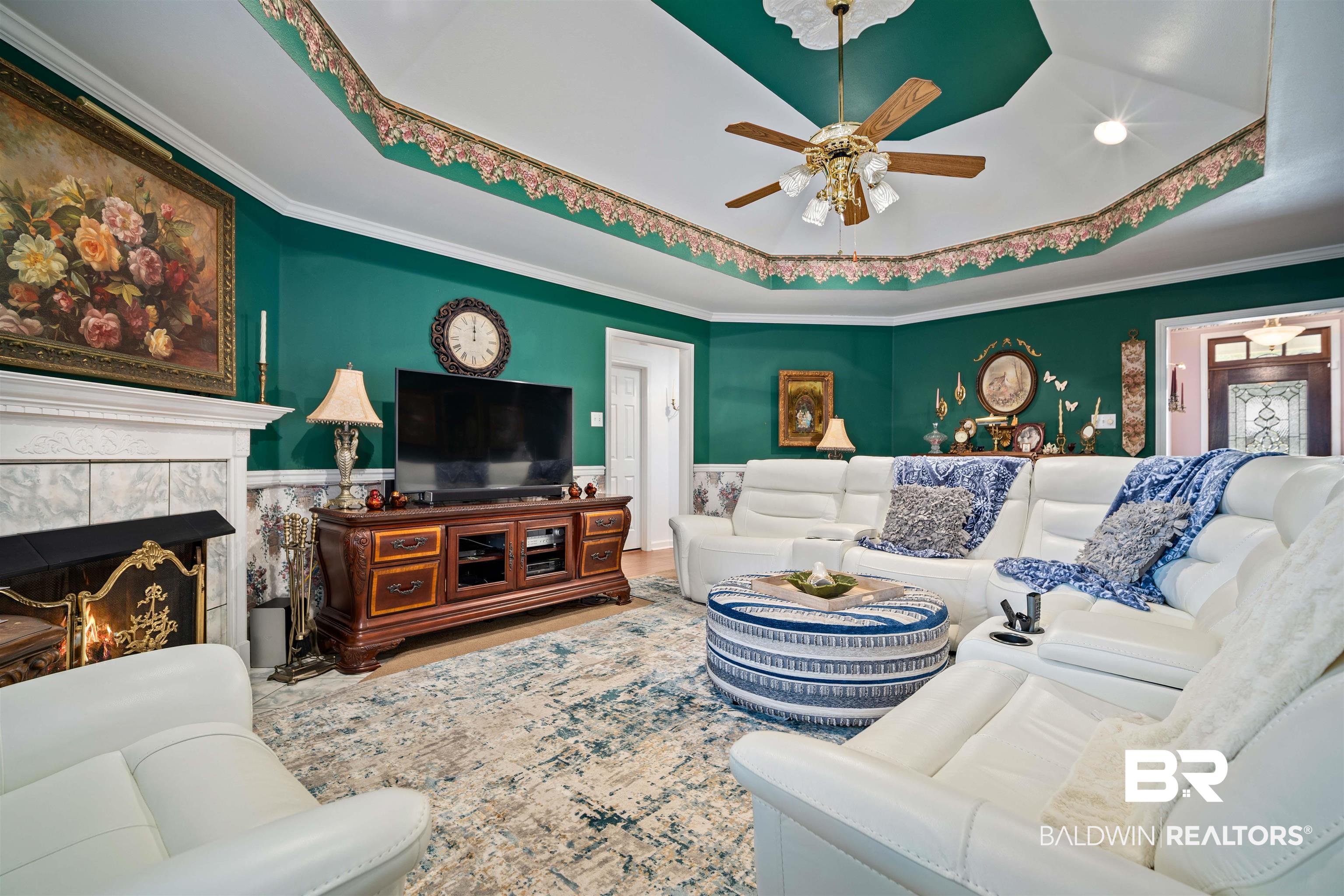 1744 Aden Road Mobile, AL 36695 - Photo 5 of 35 Living room with ceiling fan, a tiled fireplace, a tray ceiling, and crown molding
