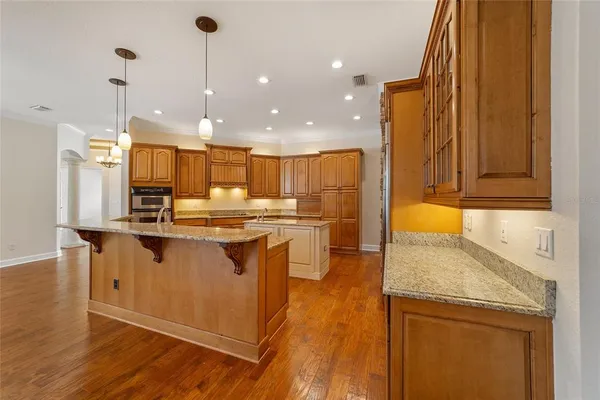 a large kitchen with stainless steel appliances granite countertop plenty wooden cabinets counter space and wooden floor