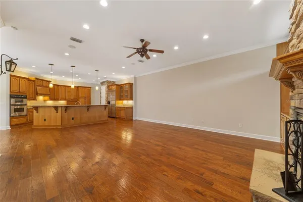 a view of an empty room with wooden floor and a kitchen