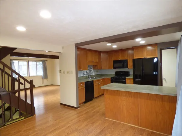 a large kitchen with stainless steel appliances wooden floor and a refrigerator