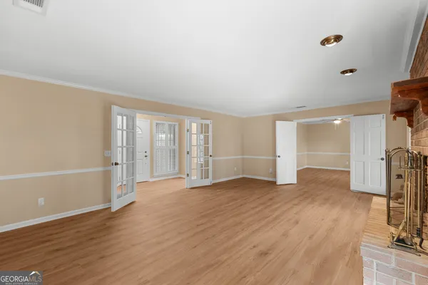 a view of empty room with wooden floor and fan