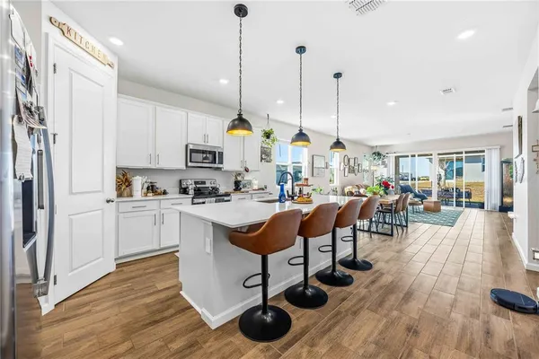 a kitchen with stainless steel appliances granite countertop a stove a sink dishwasher a refrigerator white cabinets with wooden floor