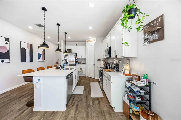 a kitchen with stainless steel appliances kitchen island granite countertop a sink a counter space cabinets and wooden floor