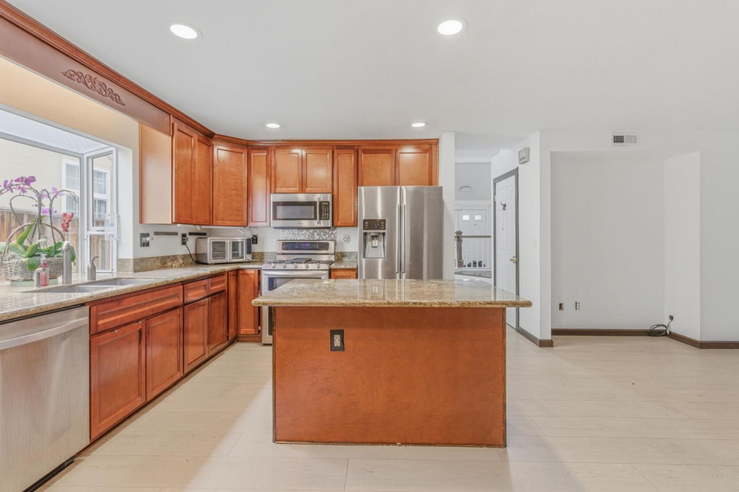 2678 Ramsdell Place San Jose, CA 95148 - Photo 21 of 41 a large kitchen with stainless steel appliances granite countertop a refrigerator a sink dishwasher a stove with wooden cabinets and floor