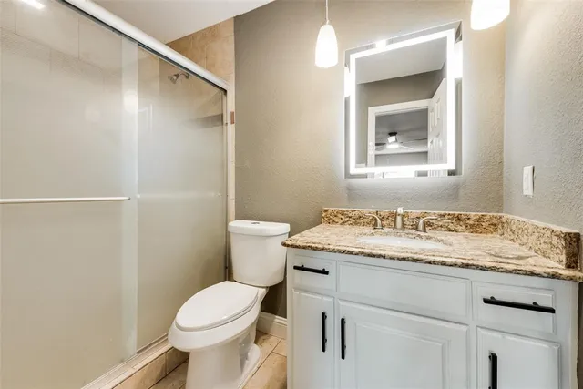 a bathroom with a granite countertop sink toilet and a mirror
