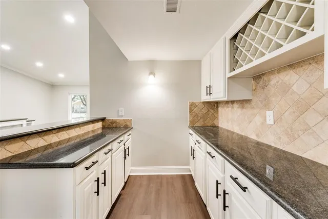 a kitchen with granite countertop a sink and dishwasher a stove top oven with wooden floor