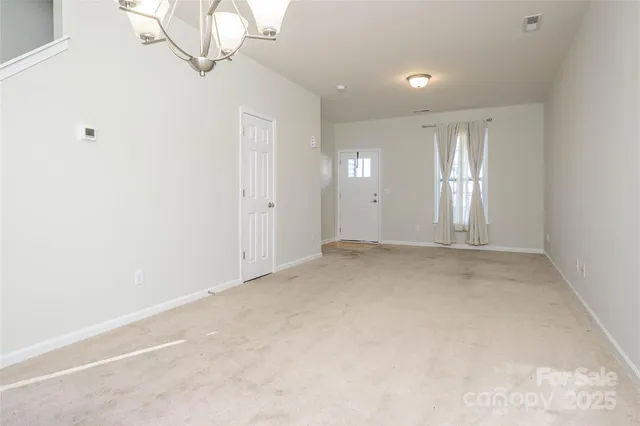 an empty room with a chandelier fan and windows