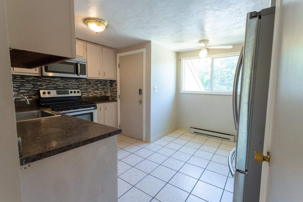 11 Tideview Path, Unit 17 Plymouth, MA 02360 - Photo 4 of 20 a kitchen with white cabinets and black appliances