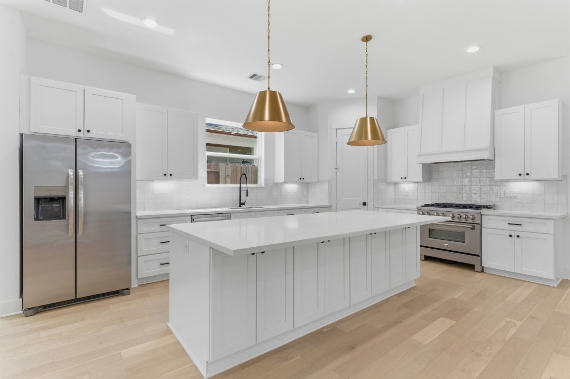 1005 Walton Street Houston, TX 77009 - Photo 11 of 36 A truly fabulous kitchen designed for style and function, featuring an oversized island with storage, quartz countertops, stainless steel appliances, and a gas range.