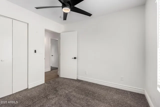 an empty room with closet and a ceiling fan