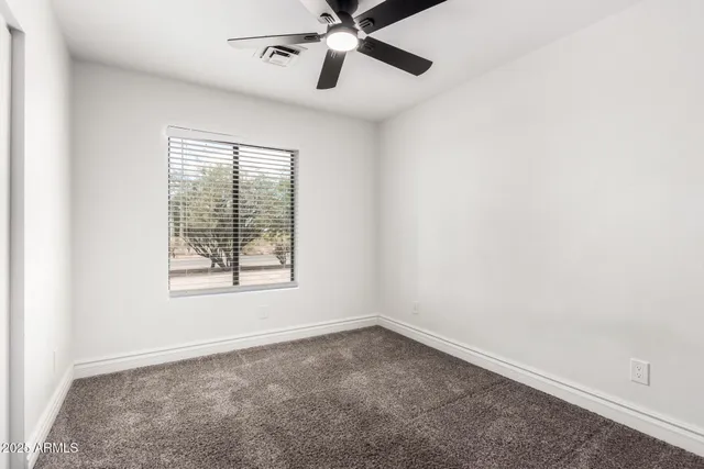 an empty room with a window and a fan