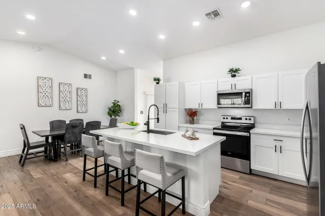 a kitchen with stainless steel appliances kitchen island granite countertop a stove a sink a dining table and chairs