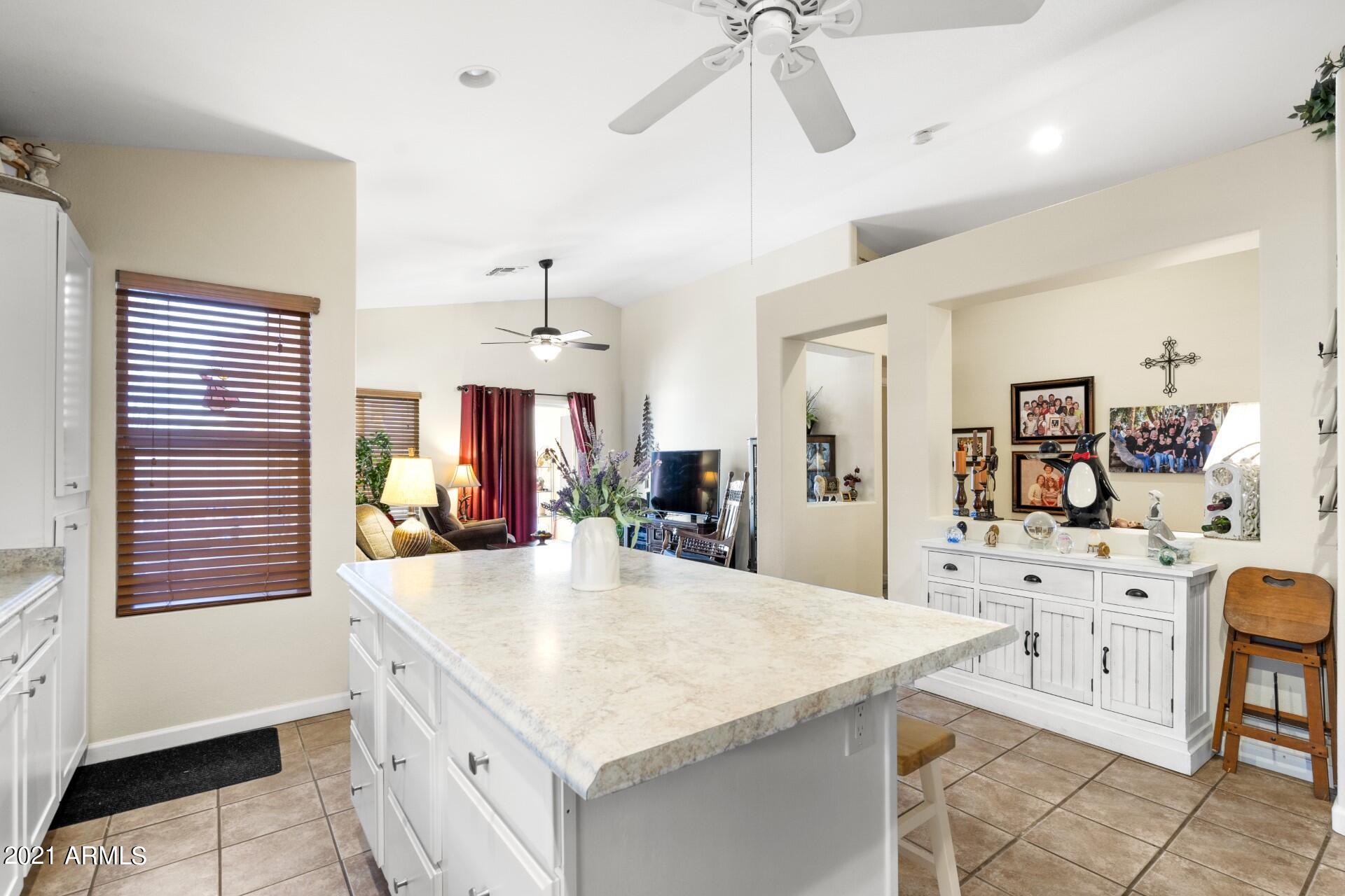 4161 West Bloomfield Road Phoenix, AZ 85029 - Photo 8 of 36 a large kitchen with kitchen island a stove a chandelier a dining table and chairs with wooden floor