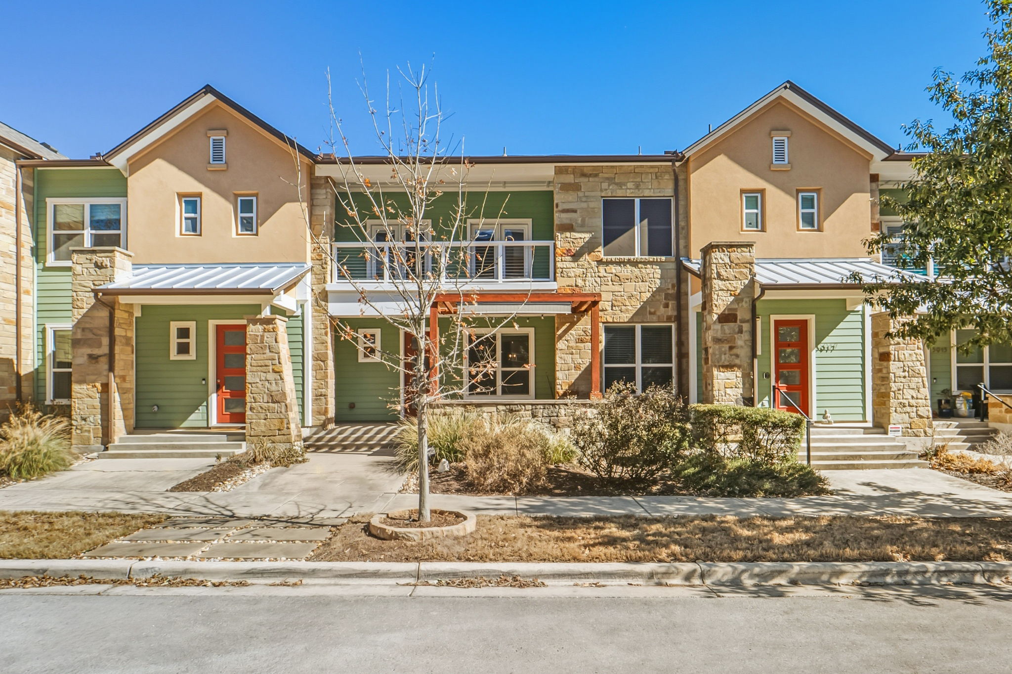 View of front facade with stone siding, a standing seam roof, stucco siding, and a porch