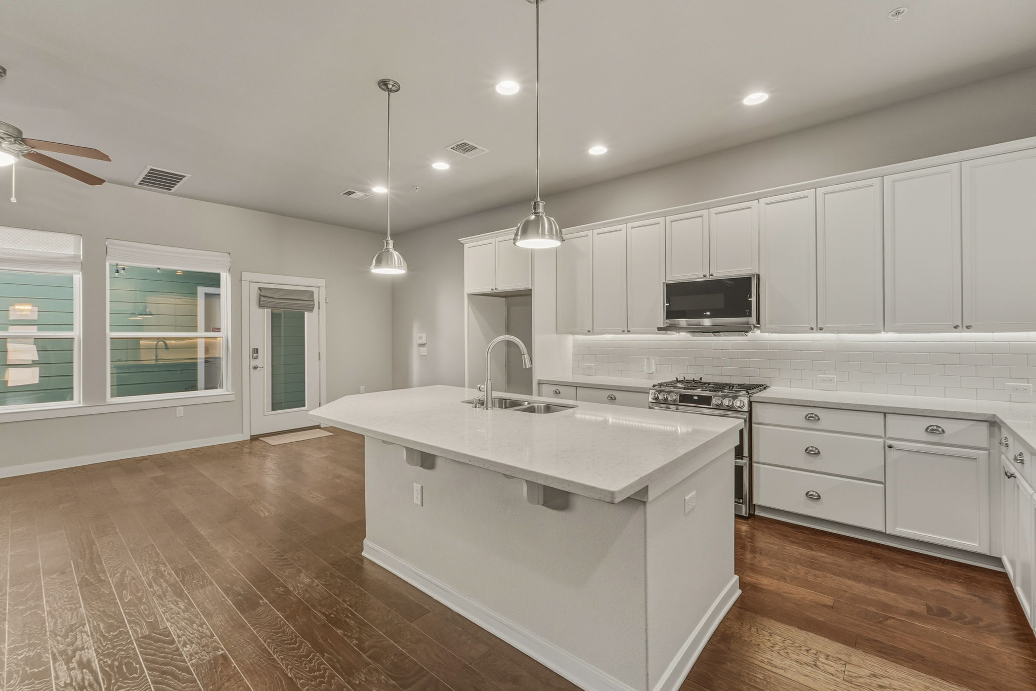 3919 Vaughan Street Austin, TX 78723 - Photo 12 of 40 Kitchen featuring white cabinetry, a kitchen island with sink, stainless steel appliances, and dark wood-style floors
