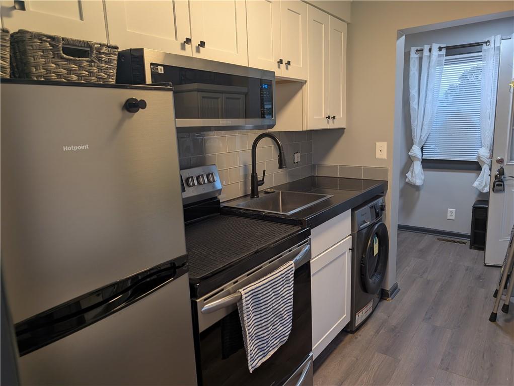 7 7th Street Bessemer, PA 16112 - Photo 4 of 24 a kitchen with stainless steel appliances a sink a stove and a refrigerator with wooden floor
