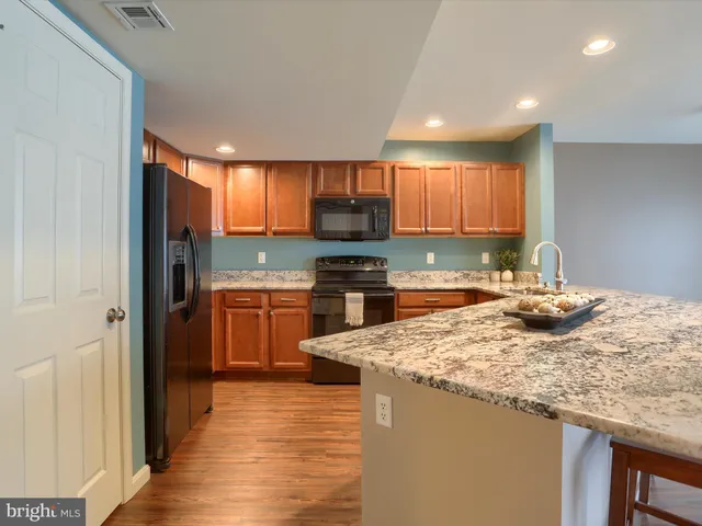 a kitchen with granite countertop a stove top oven a sink dishwasher and a refrigerator with wooden floor