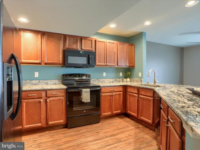 a kitchen with stainless steel appliances granite countertop wooden cabinets a stove top oven a sink and dishwasher