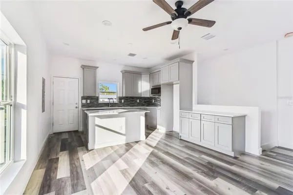 a kitchen with stainless steel appliances granite countertop a refrigerator a stove and white cabinets with wooden floor