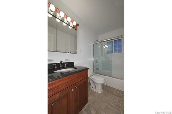 a bathroom with a granite countertop toilet sink and mirror