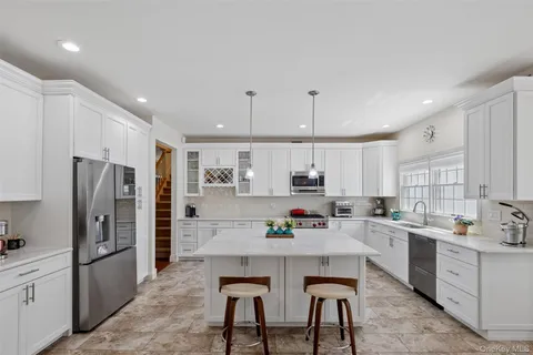 a kitchen with stainless steel appliances kitchen island granite countertop a sink a stove and white cabinets