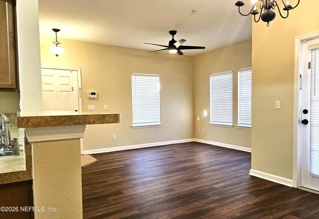 a view of an empty room with window and wooden floor