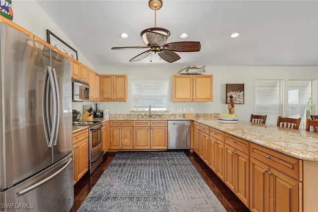 a kitchen with stainless steel appliances granite countertop a refrigerator a sink dishwasher a stove and white countertops with wooden floor