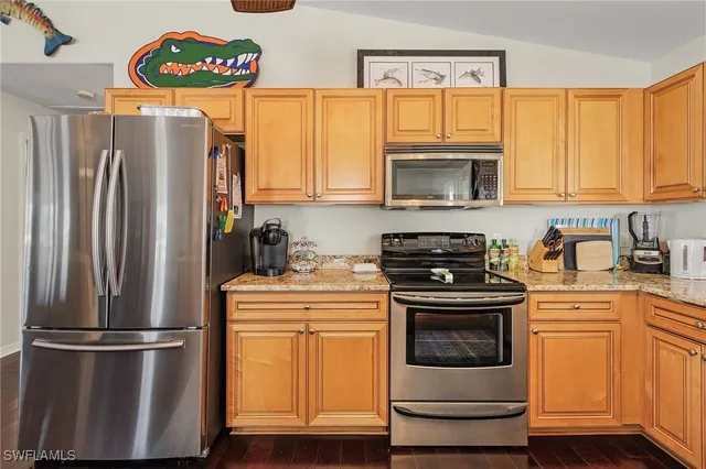a kitchen with granite countertop a refrigerator stove and microwave