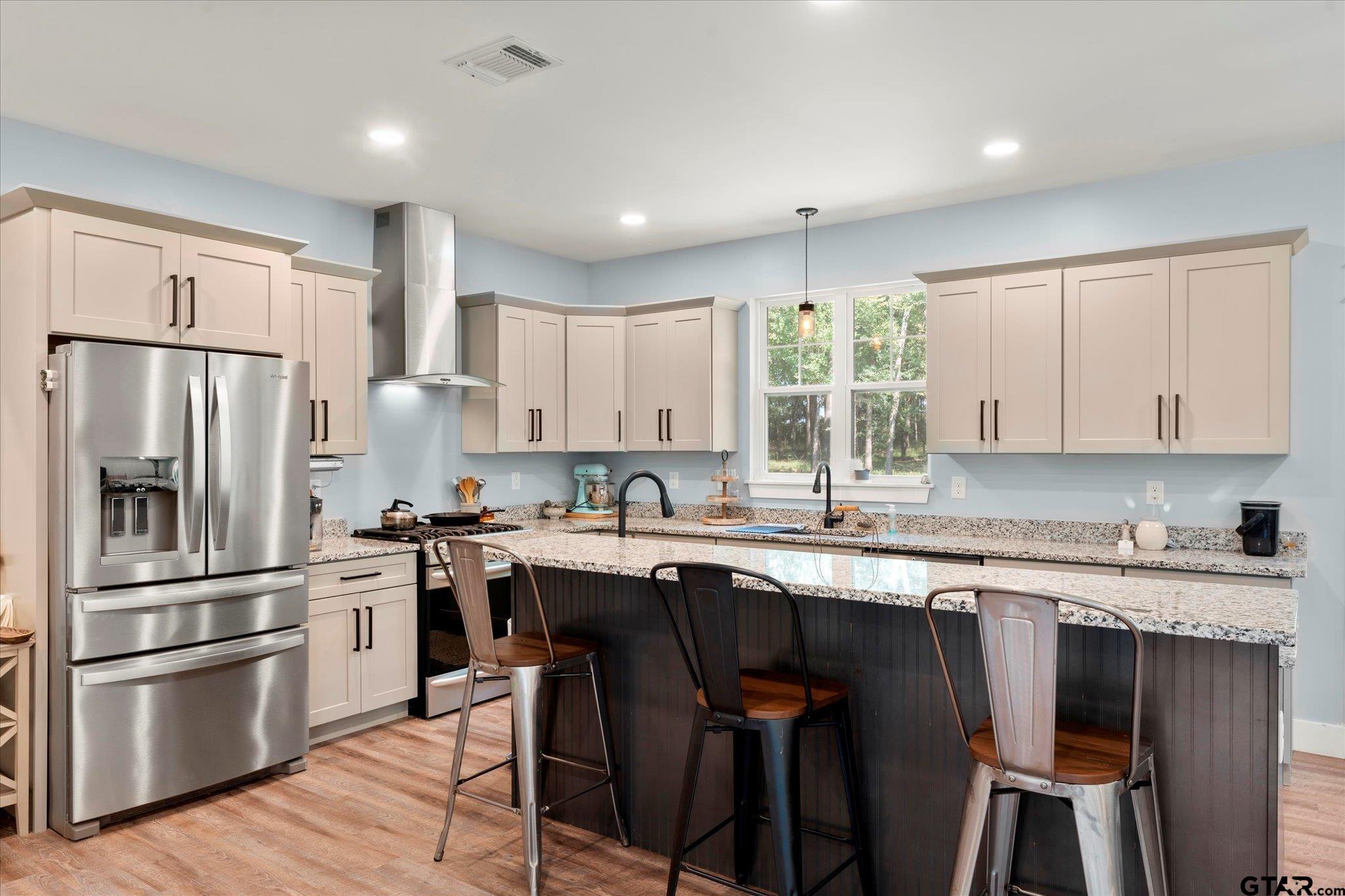 1663 County Road 4510 Pittsburg, TX 75686 - Photo 18 of 34 a kitchen with stainless steel appliances a sink a stove a refrigerator and island with wooden floor