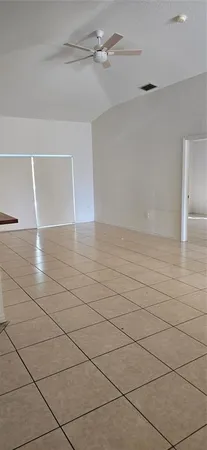 a view of an empty room and chandelier fan