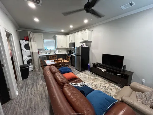 a kitchen with stainless steel appliances kitchen island granite countertop a refrigerator stove top oven dining table and chairs